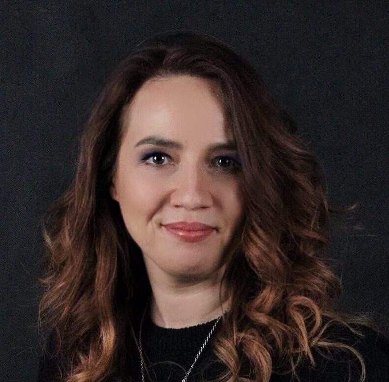 Smiling woman with curly hair on black background.